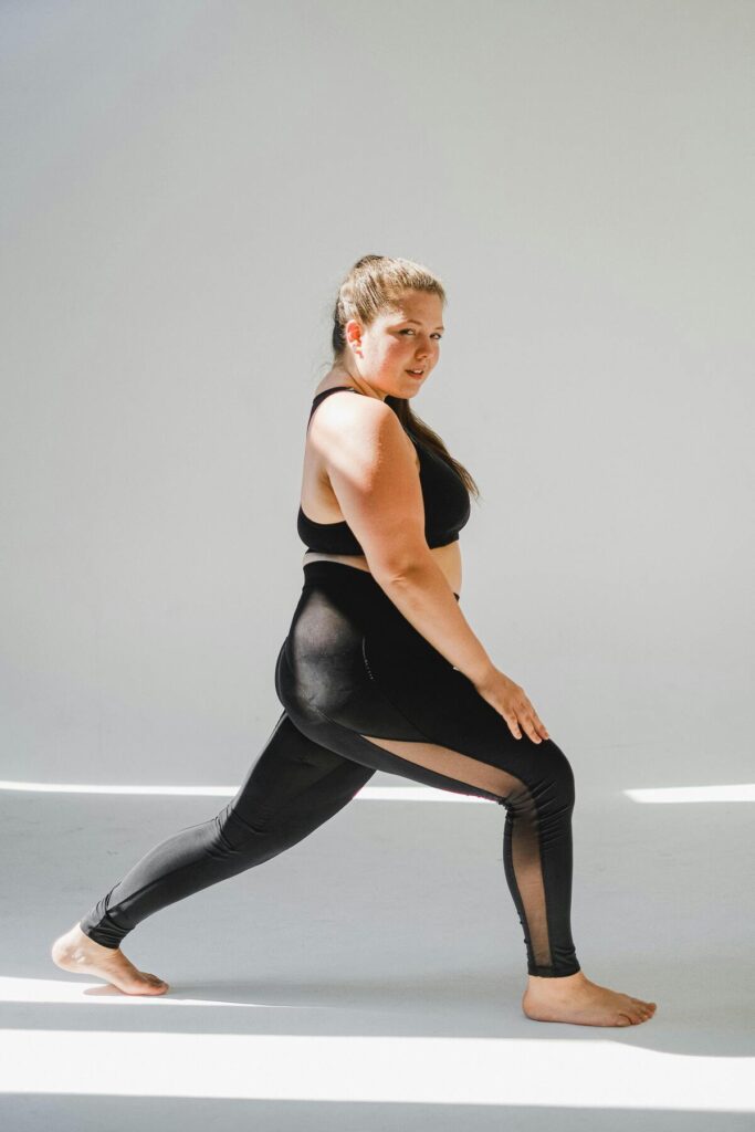 Plus size woman wearing high waist black leggings showing stretch and fit during movement